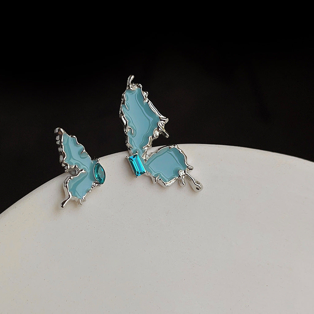 Boucle d'oreille clou asymétrique en métal avec papillon et zircon bleu