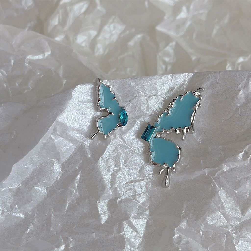 Asymmetrischer Schmetterlingsohrstecker aus Metall mit blauem Zirkon